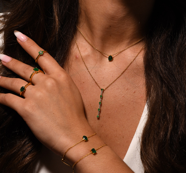 A close up shot of an emerald jewelry all stacked and layered 