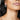 A close-up image of a woman wearing a white gold diamond earring with a round and baguette diamond design.