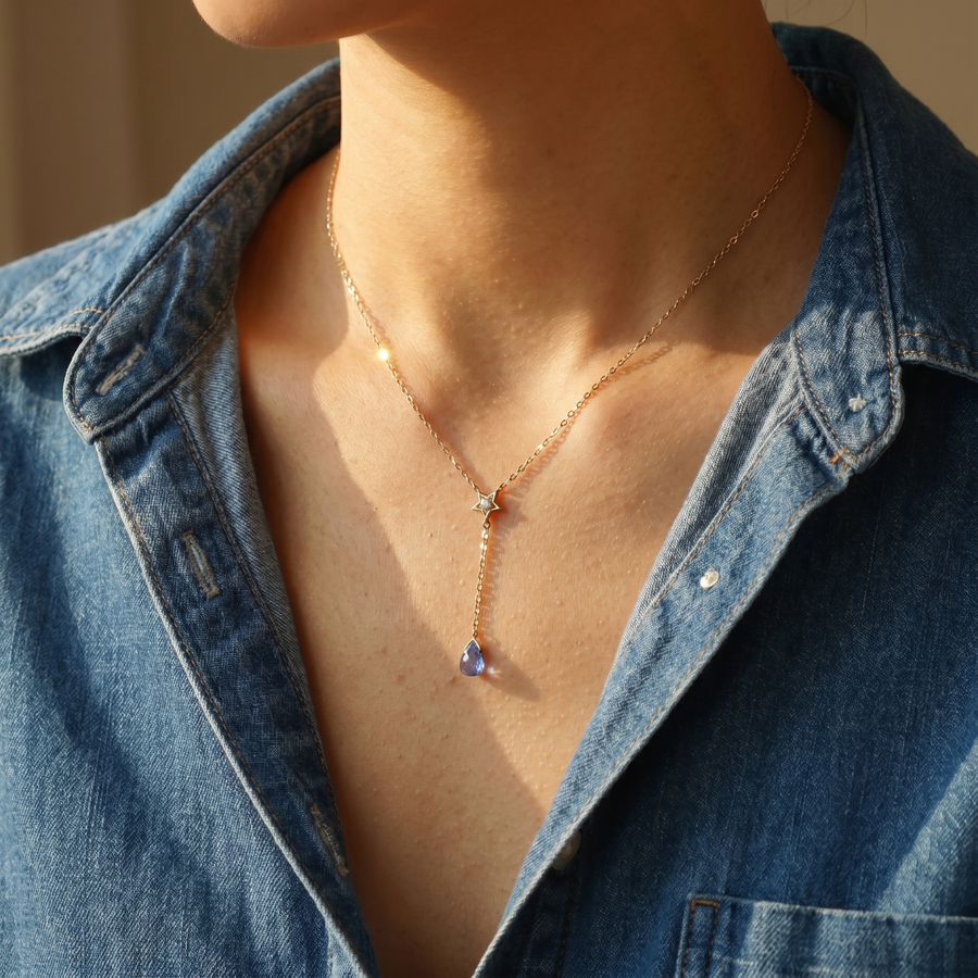 Close-up of a model wearing Alula delicate necklace with a blue pendant, set against a neutral background.