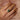 Hand wearing a 18k yellow gold zambian emerald and white sapphires gemstone ring on a soft pink fabric background
