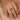 Hand wearing a 18k yellow gold zambian emerald and white sapphires gemstone ring on a soft pink fabric background