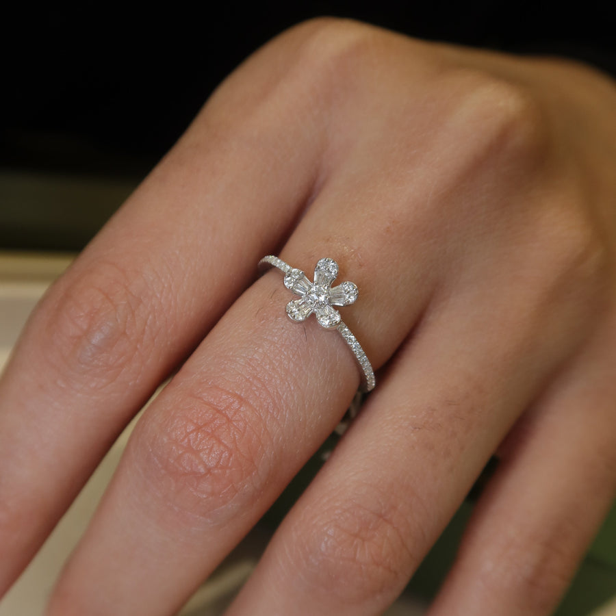 Close-up of a hand wearing a Florin Ring in white gold, in a flower-shaped ring on a neutral background