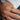 Hand wearing two natural zambian emerald green gemstones on gold rings on a blue denim background