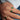 Hand wearing two natural zambian emerald green gemstones on gold rings on a blue denim background