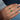 Hand wearing a gold ring with Zambian emerald gemstones against a blue fabric background