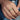 Hand wearing a Zambian emerald band ring on a blue denim background