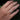 Hand wearing a white gold ring with a floral design against a blurred green background