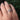 Hand wearing a white gold ring with a floral design against a blurred green background