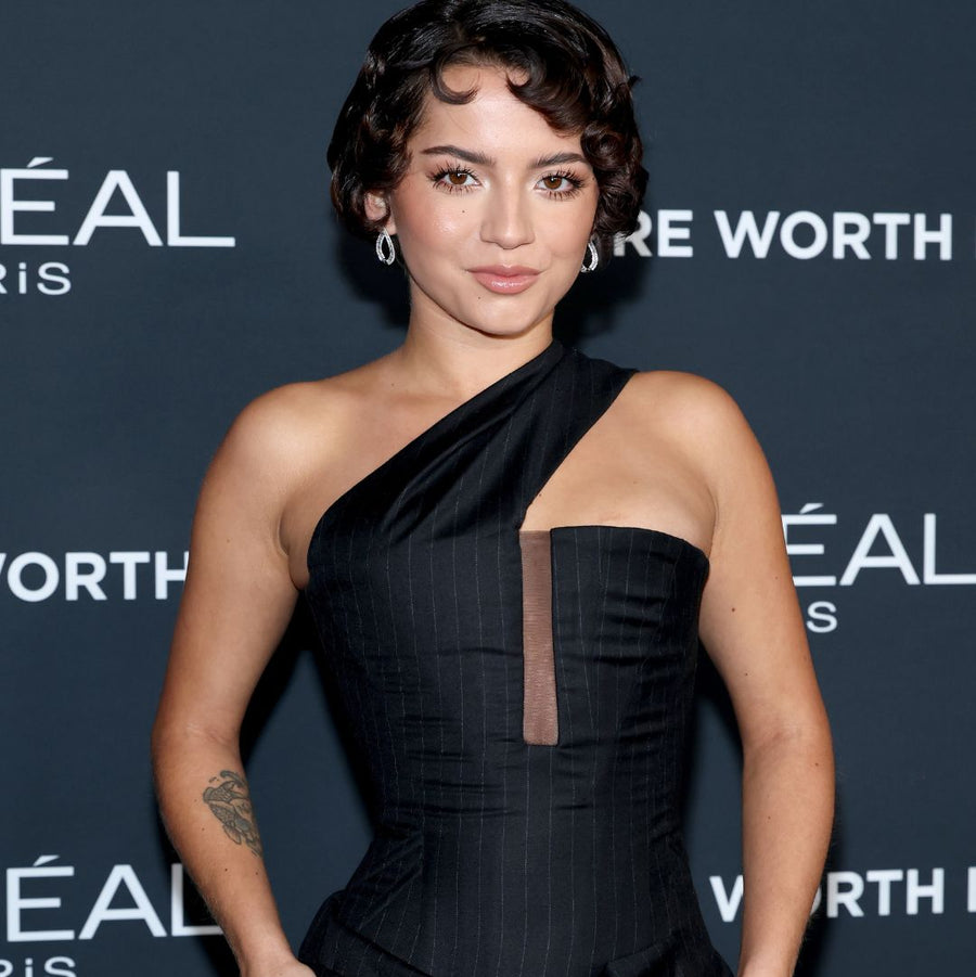 Woman in a black dress at an event with L'Oreal Paris branding.