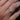 Hand wearing a white gold ring with a floral design against a blurred green background