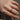 Close-up of a hand wearing a colorful sapphire ring on a neutral background