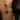 A close-up image of a person wearing 18-Karat Yellow Gold Plated on Silver earrings with an evil eye design, featuring an emerald and small round diamonds.